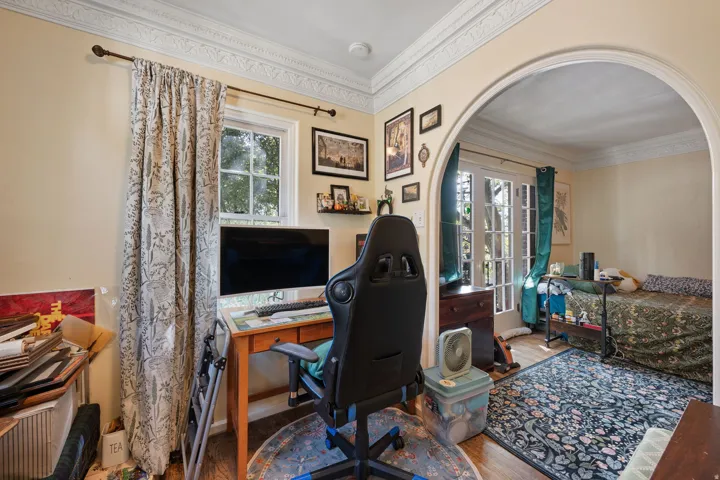 Decorative crown molding, arched doorway, wood-finish flooring, single window, double French doors