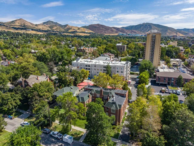 Expansive urban landscape featuring dense tree cover, multiple multi-story structures, and distant mountains