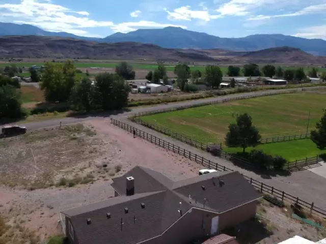 Equestrian property featuring a modern brick residence with a distinctive peaked roof design, situated on expansive grounds with multiple paddocks enclosed by post-and-rail fencing