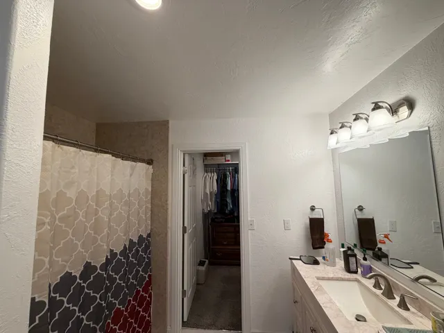 Single vanity with an integrated sink and brushed nickel faucet, illuminated by a four-light fixture