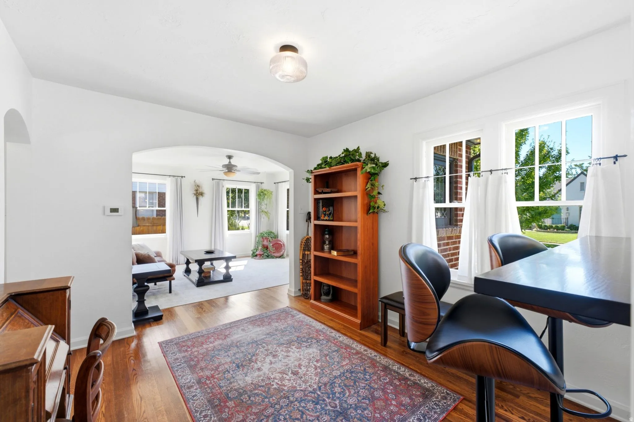 Hardwood flooring, arched doorway, recessed lighting, built-in shelving, and white interior paint