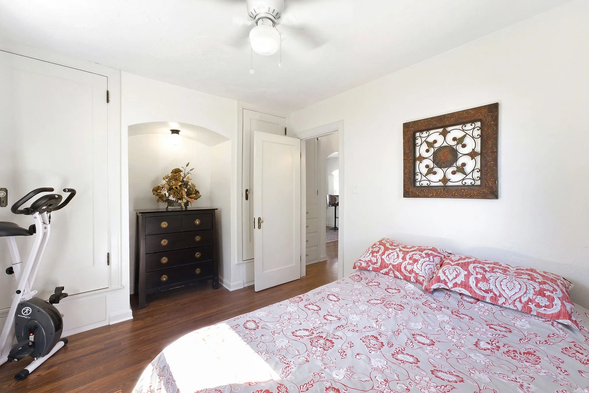 Hardwood flooring, painted white walls, ceiling fan with integrated lighting, recessed archway with lighting, and white panel doors
