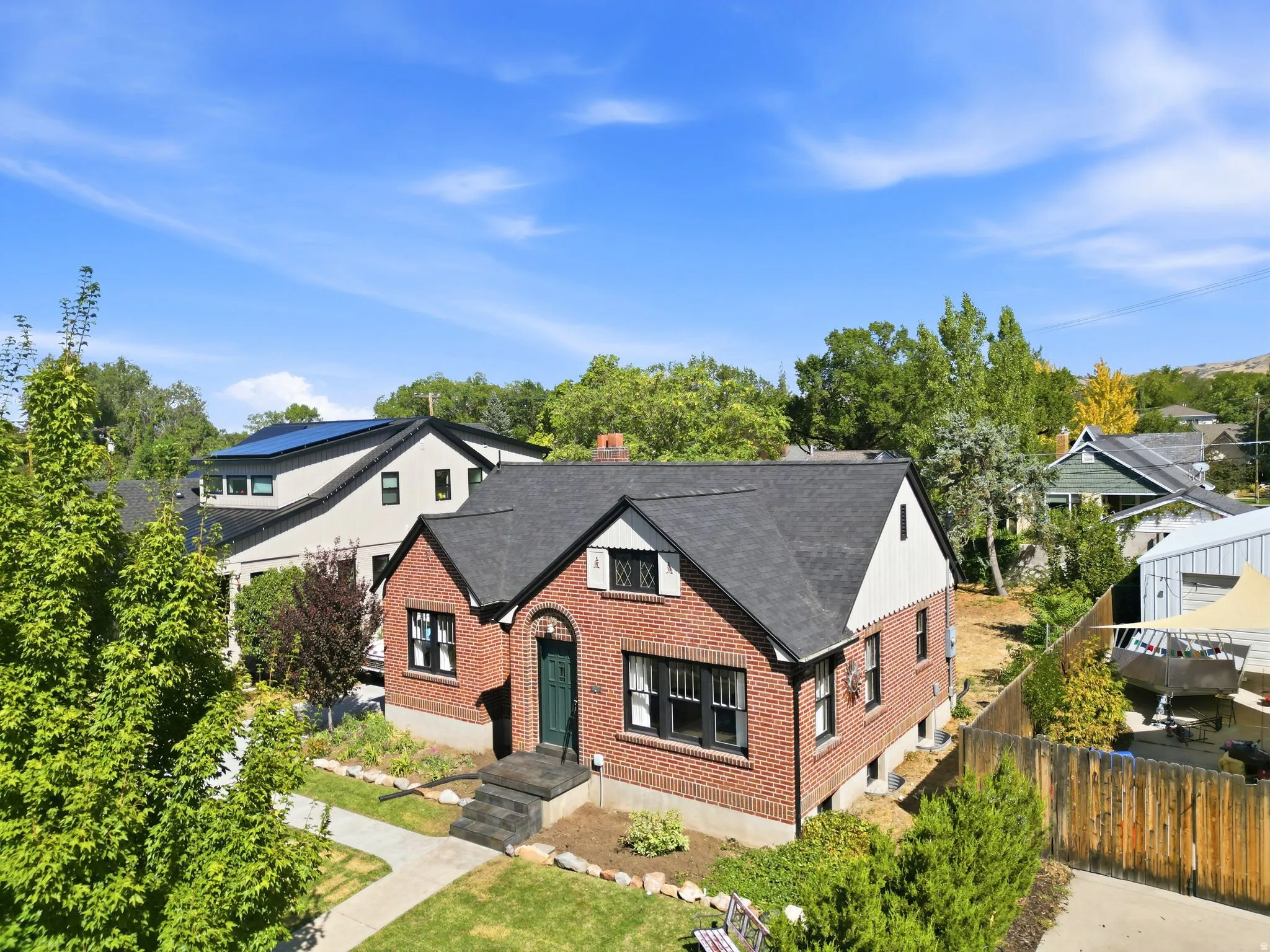 Brick exterior with contrasting white siding, dark shingled roof, arched entry, and dark window trim