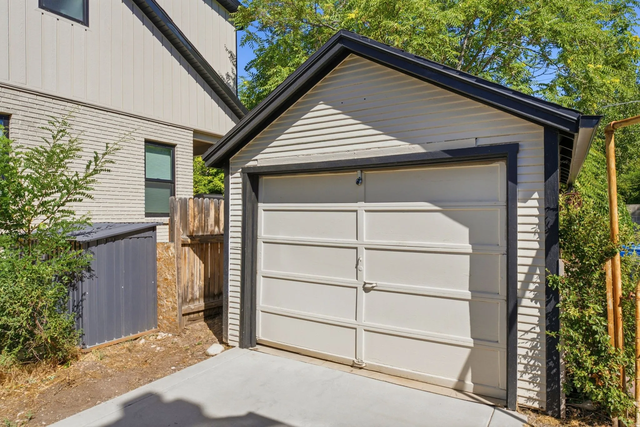 Detached garage featuring a paneled door, dark trim, and a concrete approach
