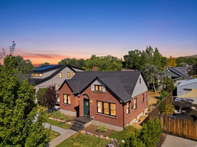 Brick exterior with a dark-pitched roof, contrasting light siding, and mature landscaping