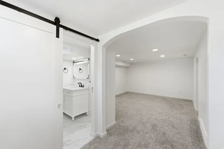 Arched doorway leading to a carpeted room with recessed lighting