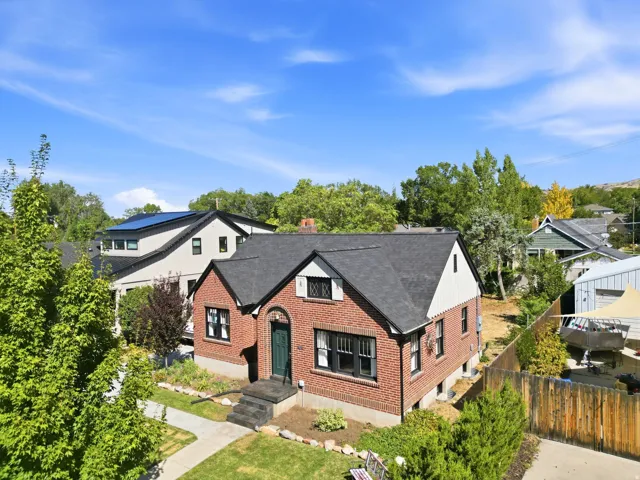 Brick exterior with contrasting white siding, dark shingled roof, arched entry, and dark window trim