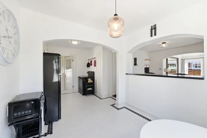 White hexagon tile flooring with black accent border, arched doorways, and a black countertop pass-through