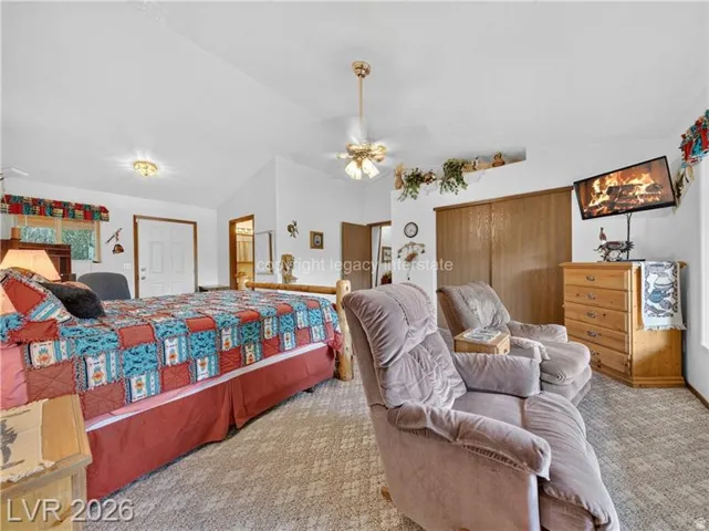Vaulted ceiling, ceiling fan, recessed shelving, wood-finish sliding closet doors, and carpeted flooring