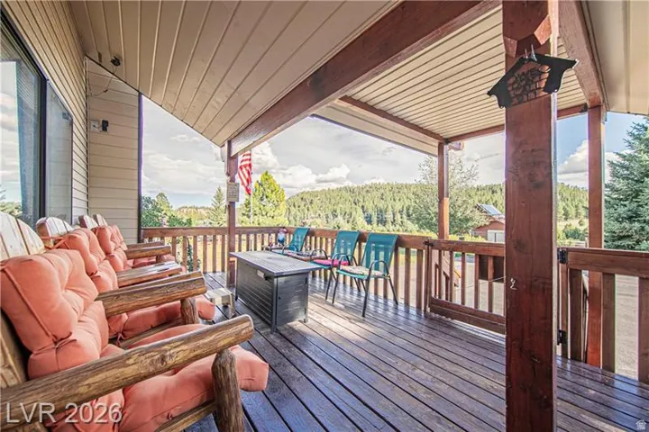 Expansive covered deck featuring a wood railing, wood-finish flooring, and a corrugated metal ceiling