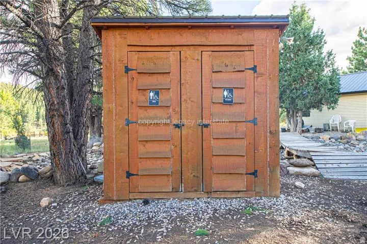 Wood-sided outbuilding with a dark metal roof and black hardware