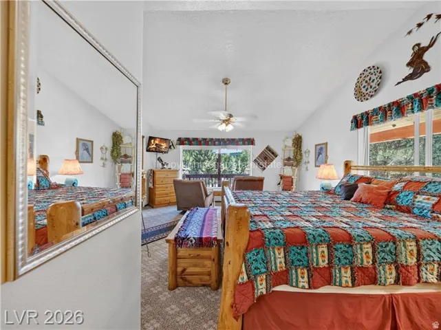 Vaulted ceilings with a ceiling fan, wall-to-wall carpeting, and wood-framed windows