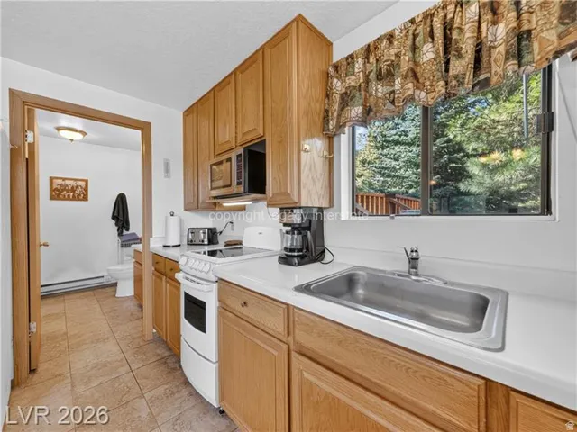 Kitchen featuring wood-finish cabinetry, solid surface countertops, a stainless steel sink, and a built-in microwave