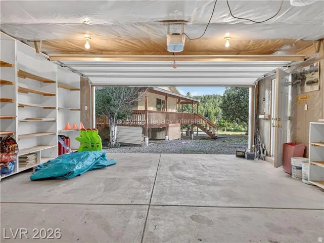 Concrete flooring with built-in shelving, two overhead light fixtures, and a garage door opener