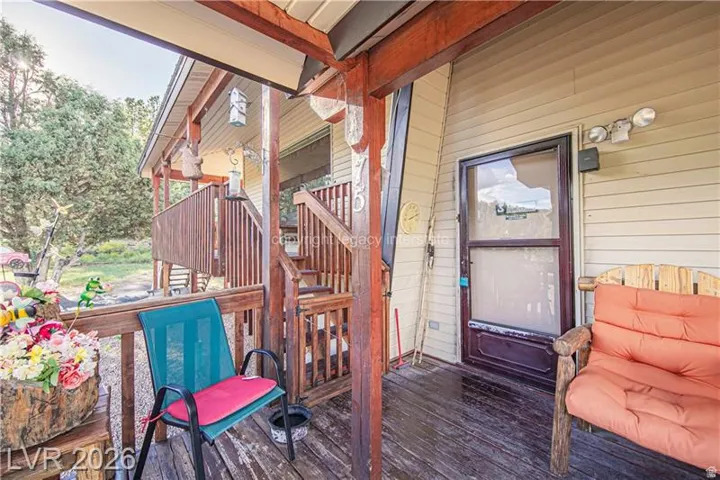 Covered porch with wood flooring and railing, siding exterior, and exterior lighting