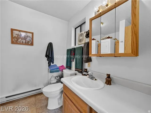 White walls complementing a light-toned countertop, wood-finish vanity with an integrated sink, and an overhead mirrored medicine cabinet with wood-finish framing