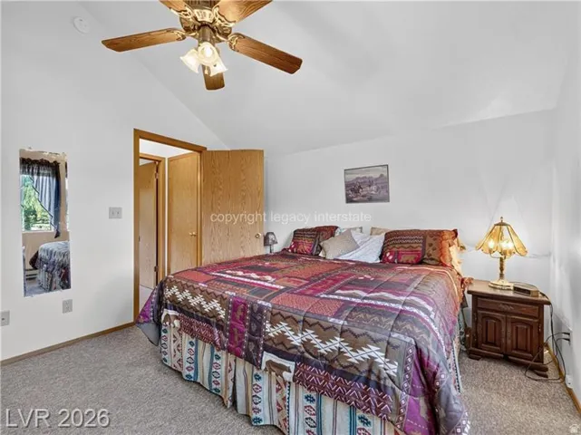 Vaulted ceiling, ceiling fan with integrated lighting, window with exterior scenery, wood-finish doors, carpet flooring