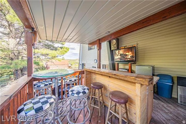 Covered outdoor deck with exposed wood beams and wood-plank flooring