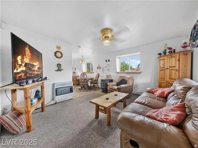 Carpeted living area with a built-in wall heater and a ceiling fan with integrated lighting