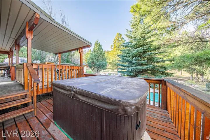 Expansive wood deck with a covered portion, featuring a hot tub and a perimeter railing