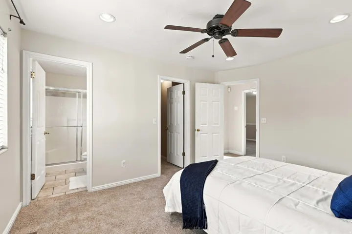 Textured carpeted flooring, a ceiling fan with integrated lighting, and recessed ceiling lights