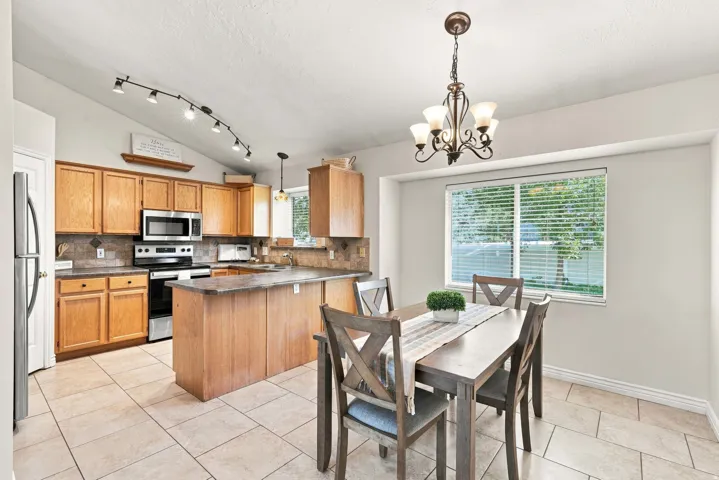 Kitchen featuring wood cabinetry, stainless steel appliances, tile backsplash, and a breakfast bar