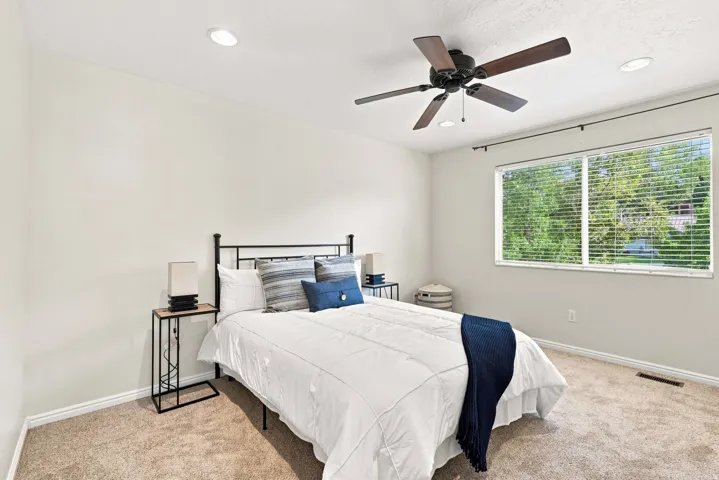 Recessed ceiling lighting, ceiling fan fixture, large window with blinds, and neutral wall tones