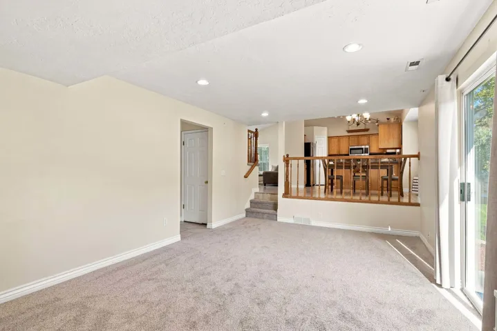 Plush carpet flooring, recessed lighting, and a sliding glass door