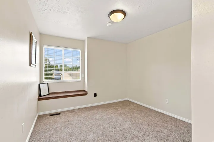 Window with blinds, wood-finish window seat, neutral carpet, and flush mount lighting