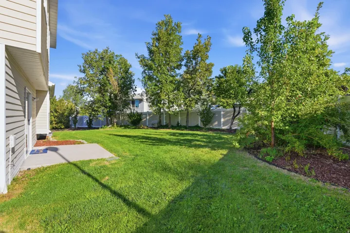 Expansive green lawn with mature trees and a concrete patio