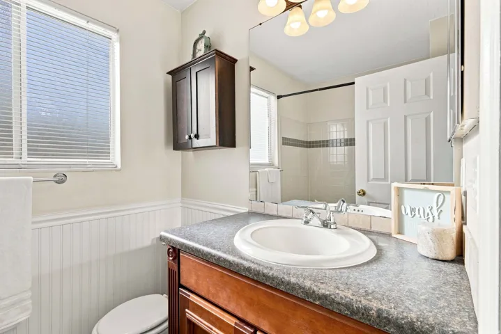 Vanity with a built-in sink and stone-finish countertop, wood-finish cabinetry, and overhead lighting