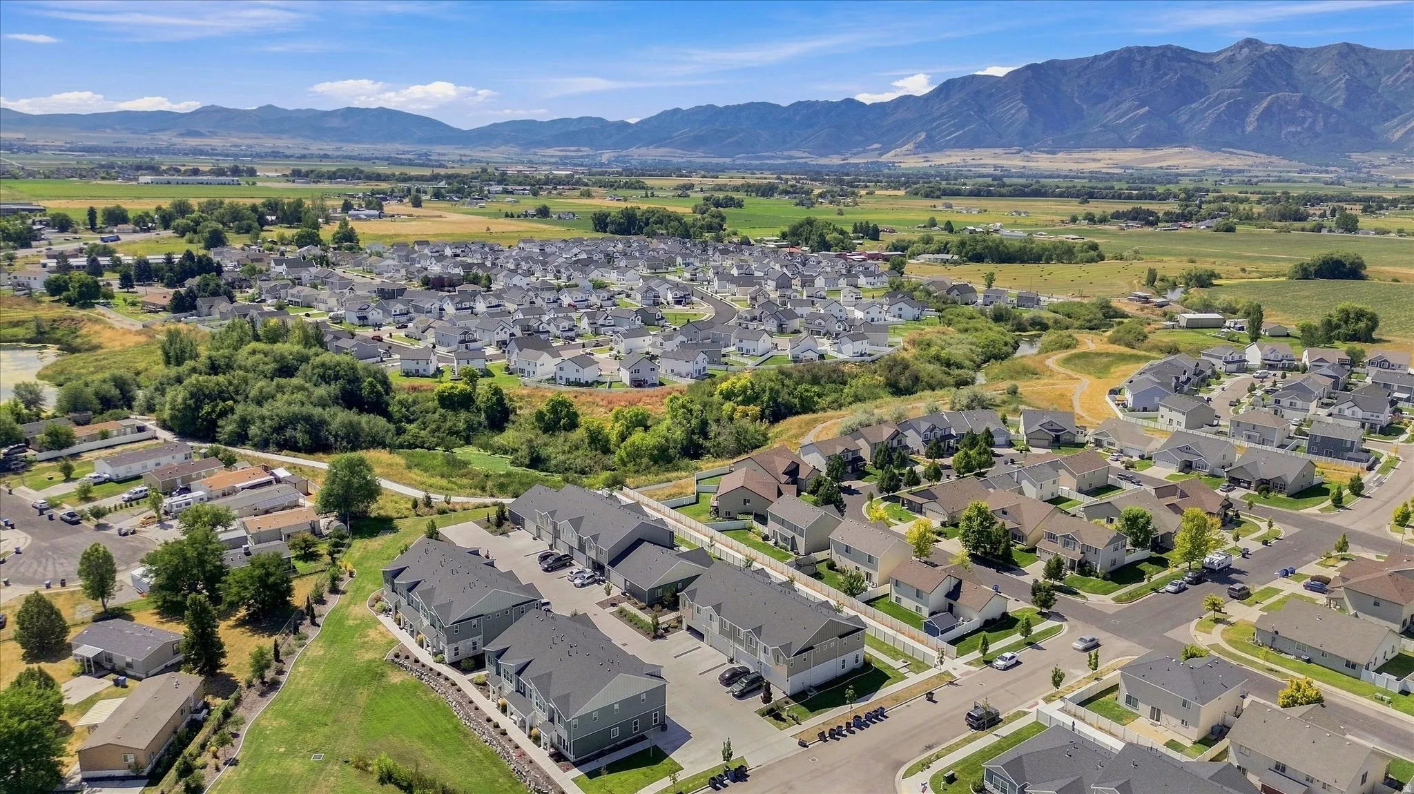 Aerial view showcasing a well-planned residential community nestled in a verdant valley with mature landscaping throughout the neighborhood