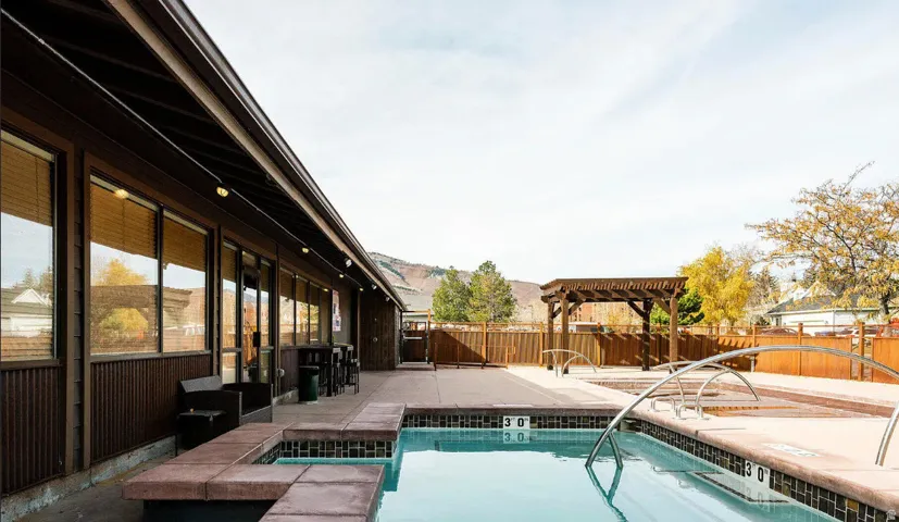 Outdoor aquatic area with a swimming pool, integrated spas, and a wooden pergola structure