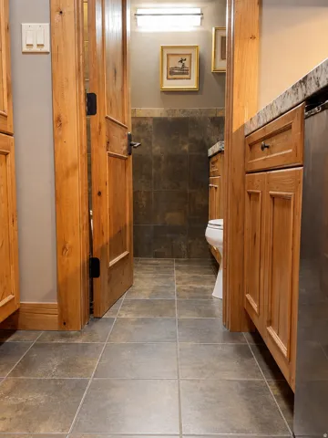 Tile flooring, wood-finish cabinetry, and a vanity with a stone countertop