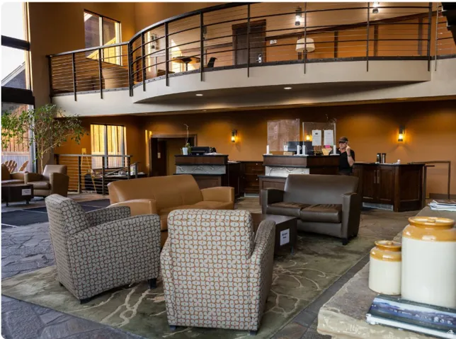 Two-story reception area featuring an open mezzanine with metal railings, a stone-finish floor, and built-in reception desks