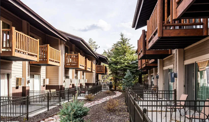 Multi-level building with individual balconies, sliding glass doors, and a decorative rock-lined pathway