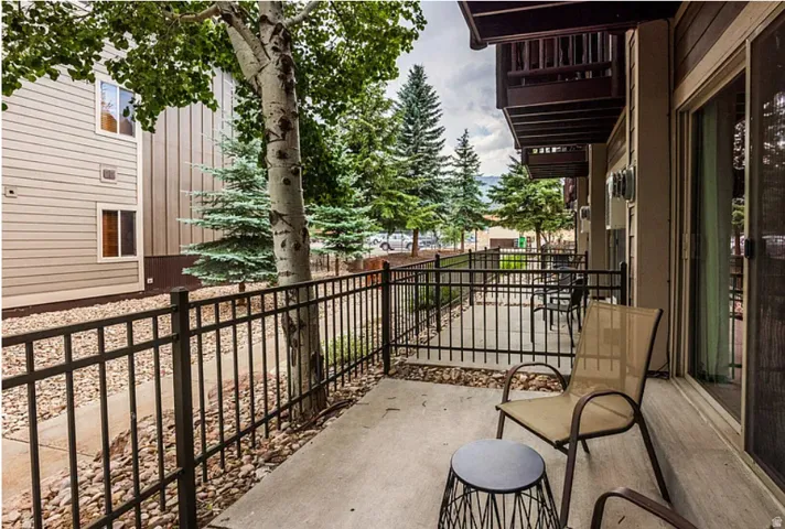 Concrete patio with a black metal railing and sliding glass door access