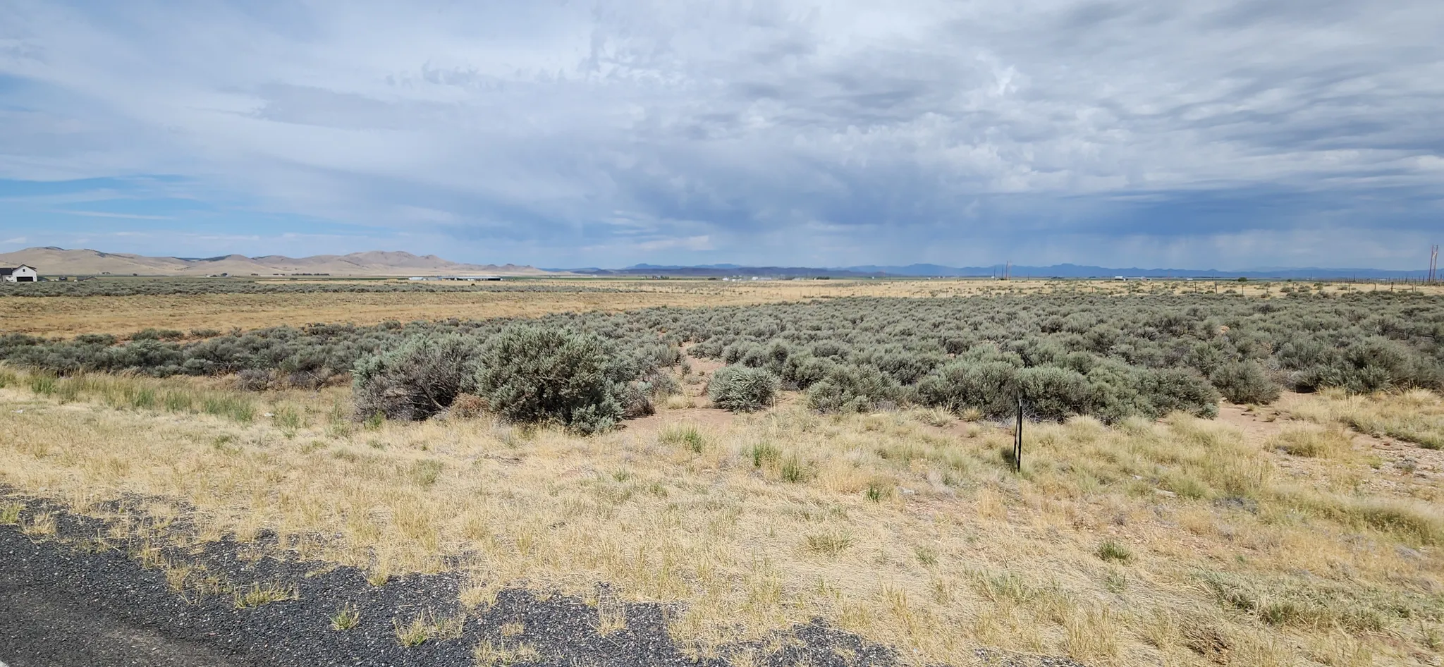 Expansive open land featuring diverse vegetation and distant mountain ranges