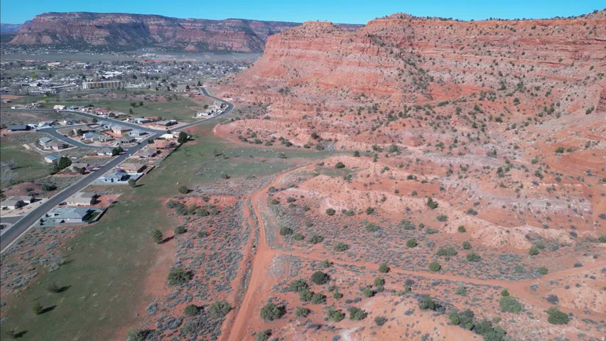 Red rock terrain and distant residential structures