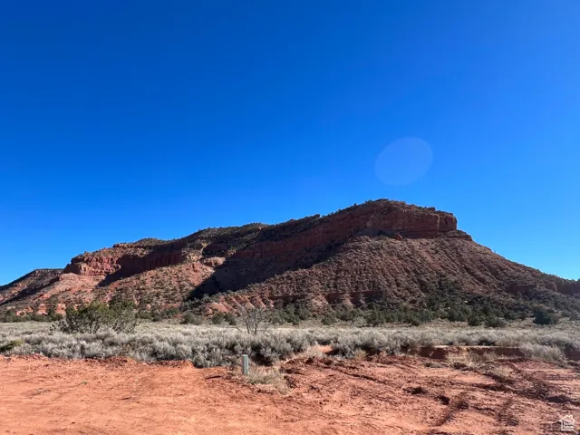 Expansive red rock terrain with diverse scrub brush and a clear sky