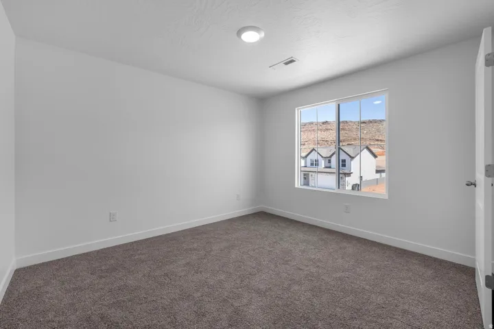 Recessed ceiling light, neutral wall paint, white trim, brown carpet flooring, and a window with mountain scenery