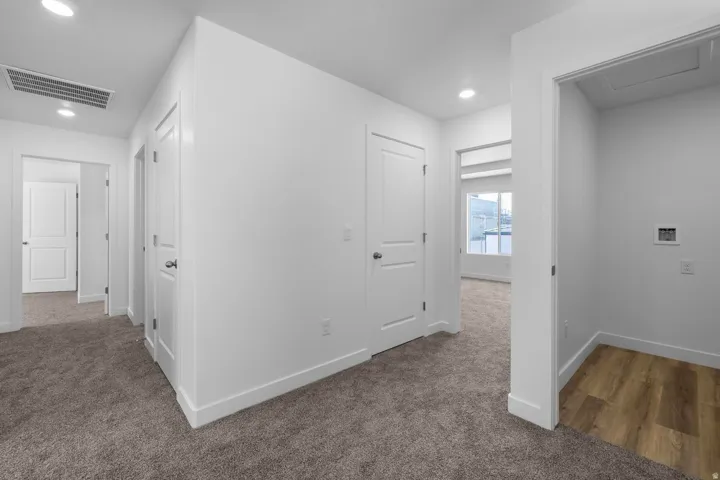 Hallway featuring recessed lighting, white interior doors, and neutral carpeting