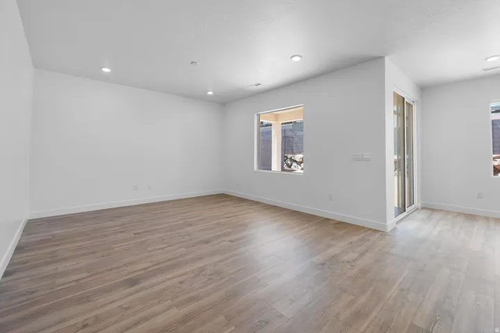 Recessed lighting, wood-finish flooring, white walls, large window, and sliding glass door