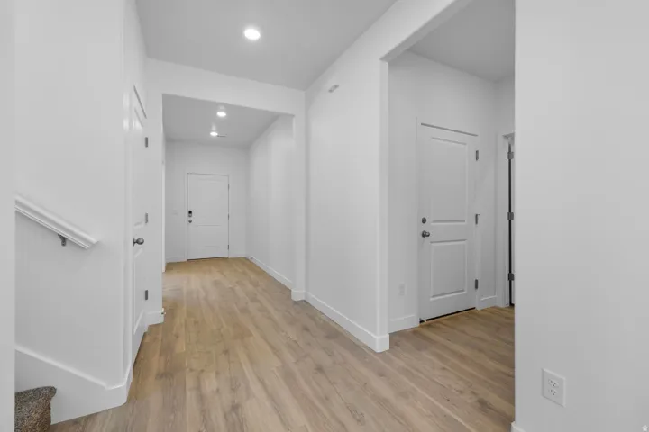 Neutral wall finishes, recessed lighting, wood-finish flooring, and white trim