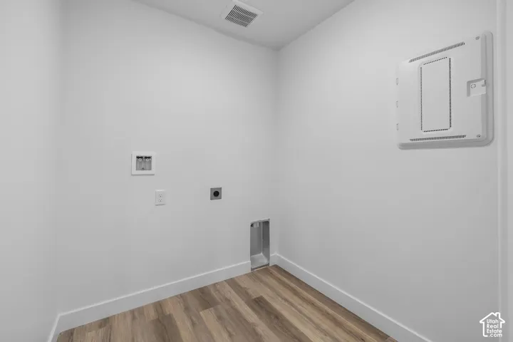Utility space featuring wood-finish flooring, white walls, and a ceiling-mounted ventilation grate