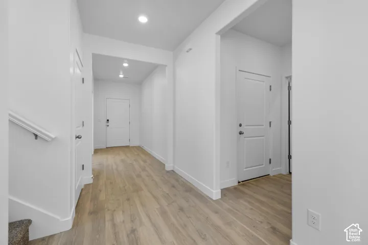 Neutral wall finishes, recessed lighting, wood-finish flooring, and white trim
