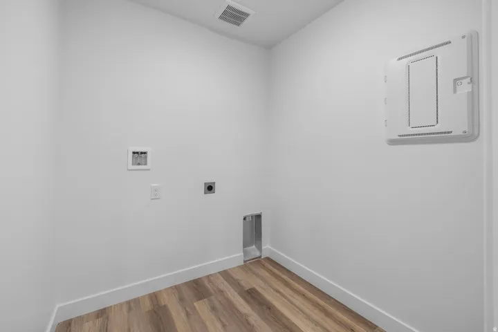 Utility space featuring wood-finish flooring, white walls, and a ceiling-mounted ventilation grate