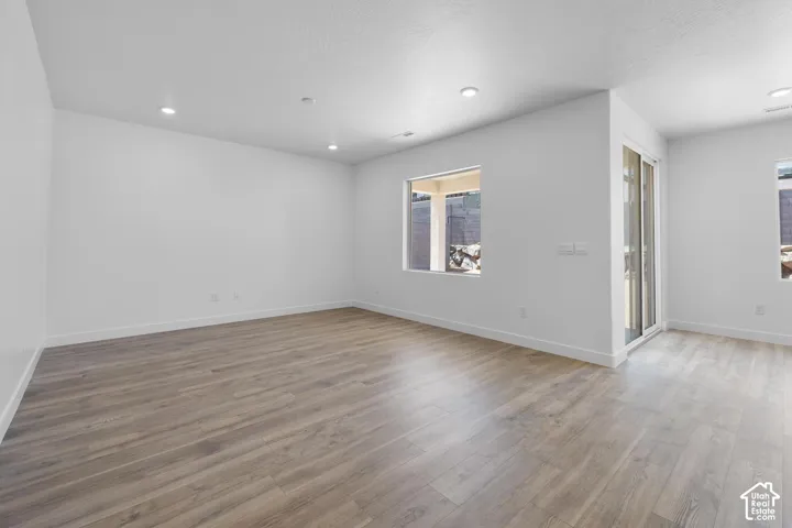 Recessed lighting, wood-finish flooring, white walls, large window, and sliding glass door