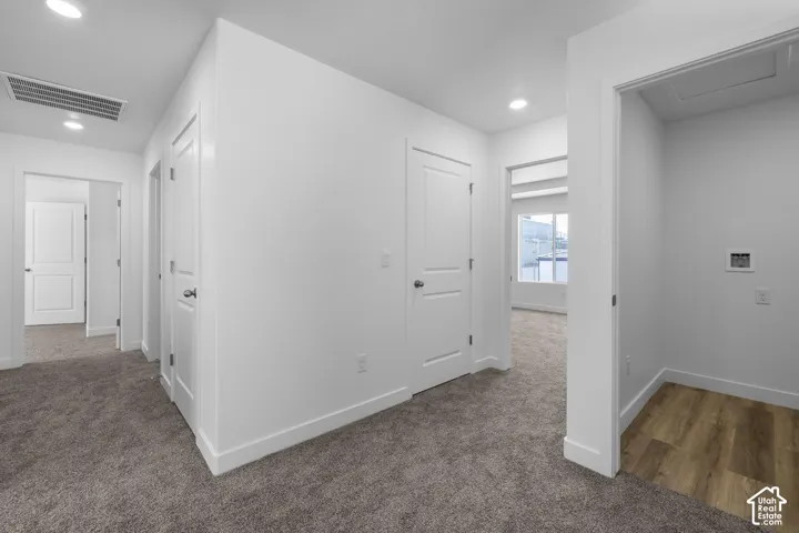 Hallway featuring recessed lighting, white interior doors, and neutral carpeting
