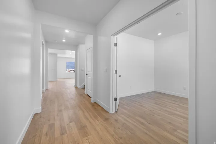 Hallway featuring wood-finish flooring, recessed lighting, and a white interior door